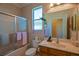Bathroom featuring tiled walls, a shower-tub combo with glass door, and window for natural light at 13968 Se 96Th Cir, Summerfield, FL 34491