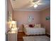 A cozy bedroom with wood floors, pink walls, ceiling fan, desk and natural lighting at 13968 Se 96Th Cir, Summerfield, FL 34491
