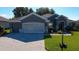 Charming home featuring a gray exterior, well-maintained lawn, and a stylish brick driveway at 13968 Se 96Th Cir, Summerfield, FL 34491