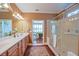 An open-concept bathroom featuring double sinks, a marble vanity and a glass shower with a stained glass window at 13968 Se 96Th Cir, Summerfield, FL 34491