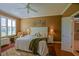 This main bedroom features a ceiling fan, a plush bed, and an open door to the main bathroom at 13968 Se 96Th Cir, Summerfield, FL 34491