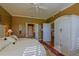 This bedroom features a ceiling fan, wood floors, a plush bed and a doorway to another room at 13968 Se 96Th Cir, Summerfield, FL 34491