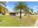 View of the backyard from the lawn showcasing the screen enclosed lanai and mature landscaping at 12240 Se 172Nd Ln, Summerfield, FL 34491