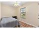 The bedroom features a window with blinds, hardwood flooring, a grey comforter, and neutral colored walls at 12240 Se 172Nd Ln, Summerfield, FL 34491