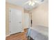 Bedroom featuring hardwood floors, a grey comforter, and a ceiling fan with easy access to other rooms at 12240 Se 172Nd Ln, Summerfield, FL 34491