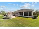 View of the home's back exterior featuring a brick patio, lovely landscaping, and a screened in lanai at 2380 Nw 55Th Avenue Rd, Ocala, FL 34482