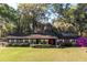 Brick home featuring a cozy front porch with rocking chairs, set in a lush, grassy yard at 2570 Se Highway 42, Summerfield, FL 34491