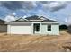 Charming single-story home with a two-car garage, light blue paint, and a well-maintained yard under a cloudy sky at 4504 Sw 90Th Lane Rd, Ocala, FL 34476
