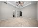 Spacious bedroom features a ceiling fan, tray ceiling, carpet, and ensuite bathroom access at 5048 Sw 57Th Pl, Ocala, FL 34474