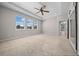 Large main bedroom with three windows, tray ceiling with fan, and neutral carpet flooring at 5048 Sw 57Th Pl, Ocala, FL 34474