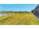 Scenic backyard with a lush lawn extending to a peaceful lake with distant homes at 6558 Sw 94Th Cir, Ocala, FL 34481