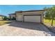 Well-lit two-car garage with a decorative tree beside a paver driveway for this single-Gathering home at 6558 Sw 94Th Cir, Ocala, FL 34481