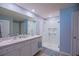 Bathroom featuring double sinks, a walk-in glass shower, and blue walls at 6933 Se 111Th Ln, Belleview, FL 34420
