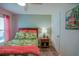 Cozy bedroom showcases wood floors, a tropical print bedspread, and a charming pineapple lamp at 6933 Se 111Th Ln, Belleview, FL 34420