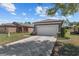 Home exterior featuring a two-car garage, manicured landscaping, and a spacious driveway and neutral paint scheme at 7665 Sw 96Th Avenue Rd, Ocala, FL 34481
