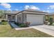 Charming home exterior featuring a two-car garage, manicured landscaping, and a pathway to the front door at 7665 Sw 96Th Avenue Rd, Ocala, FL 34481