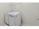 Efficient laundry room with a modern washer and dryer set, tiled floor, and upper shelving at 7665 Sw 96Th Avenue Rd, Ocala, FL 34481