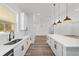 Modern kitchen features white cabinets, stainless appliances, oversized island with pendant lights, and Luxury Vinyl Plank flooring at 8850 Sw 125Th Ter, Dunnellon, FL 34432