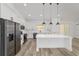 Modern kitchen with white cabinets, stainless steel refrigerator, oversized island, pendant lights and vinyl plank flooring at 8850 Sw 125Th Ter, Dunnellon, FL 34432