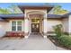 Welcoming facade featuring an arched entryway, well-maintained landscaping, and double front doors at 8869 Sw 194Th Ct, Dunnellon, FL 34432