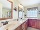Elegant bathroom featuring double sinks, a spacious vanity, decorative mirrors, and a glass-enclosed shower at 11010 Se 174Th Loop, Summerfield, FL 34491