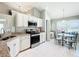 Bright kitchen featuring white cabinets, granite countertops, stainless steel appliances, and an adjacent breakfast nook at 11010 Se 174Th Loop, Summerfield, FL 34491