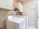 Practical laundry room equipped with modern washer and dryer, plus ample storage in white cabinets at 11010 Se 174Th Loop, Summerfield, FL 34491