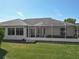 This is an appealing view of the screened-in lanai and exterior facade from the verdant backyard at 11010 Se 174Th Loop, Summerfield, FL 34491
