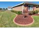 Side yard with grass, decorative red rock mulch, manicured bushes, and partial view of neighbor's house at 11395 Sw 139Th St, Dunnellon, FL 34432