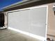 Garage door screen with white trim installed on a tan stucco house with a white gutter at 13780 Sw 111Th Ave, Dunnellon, FL 34432