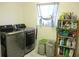 Laundry room with modern washer and dryer, window, and functional storage shelving at 13780 Sw 111Th Ave, Dunnellon, FL 34432