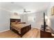 Comfortable bedroom with ceiling fan, wood floors, and a large wooden bed with an assortment of drawers at 13805 Se 87Th Ter, Summerfield, FL 34491