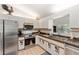 Well-equipped kitchen features stainless steel appliances, white cabinetry, and tile flooring, enhancing functionality and style at 13805 Se 87Th Ter, Summerfield, FL 34491