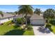 Well-maintained single-story home featuring a landscaped front yard, mature palm trees, and a two-car garage at 1689 Van Buren Way, The Villages, FL 32162