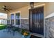 Inviting front porch featuring stone accents, potted plants, and a sleek black front door at 1861 Ne 50Th Ter, Ocala, FL 34470
