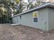 View of the back of the house with light green siding and dry lawn at 2983 Se 145Th Pl, Summerfield, FL 34491