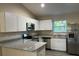 Well-equipped kitchen featuring granite countertops, stainless steel appliances, and white cabinetry at 2983 Se 145Th Pl, Summerfield, FL 34491