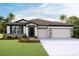Charming one-story home with a three-car garage, stone accents, manicured lawn, and a well-maintained landscape at 3063 Canopy Oak Blvd, Wildwood, FL 34785