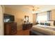 Cozy bedroom featuring a ceiling fan, dresser, television, and comfortable bed with decorative pillows at 5291 Nw 20 Pl, Ocala, FL 34482