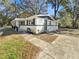 Corner view of a minimalist single-story home with gray door, black shutters, and minimalist landscaping at 5311 Nw 27Th Ave, Ocala, FL 34475