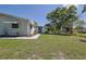 View of the backyard with green grass, mature trees and landscaping and a covered patio at 6398 Sw 108Th St, Ocala, FL 34476