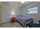 A well-lit bedroom featuring a patterned bed, grey floors and a simple white wall at 6398 Sw 108Th St, Ocala, FL 34476