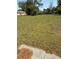 A view of the grassy backyard featuring scattered pine straw and hardscape at 6725 Nw 14Th Ave, Ocala, FL 34475