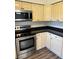 Bright kitchen featuring stainless steel appliances, wood grain flooring, and painted cabinets at 6725 Nw 14Th Ave, Ocala, FL 34475