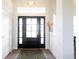 Bright entryway with a black front door with sidelights, transom window, and wood flooring at 8214 Nw 17Th Cir, Ocala, FL 34475