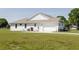 Side view of the exterior, showcasing the white siding, garage, and well-maintained lawn at 8214 Nw 17Th Cir, Ocala, FL 34475