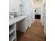 Hallway view including laundry area with white cabinets, a sink, and open shelving, connected by wood-look flooring at 8214 Nw 17Th Cir, Ocala, FL 34475