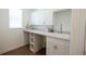 Well-lit laundry room with white cabinets, countertop, sink, and storage shelves, complemented by wood-look flooring at 8214 Nw 17Th Cir, Ocala, FL 34475