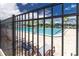 Large community pool with clear blue water, lounge chairs, umbrellas, and palm trees behind a metal fence at 8836 Sw 90Th Ln # B, Ocala, FL 34481