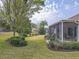 Lush backyard featuring mature trees, manicured landscaping, and a screened-in lanai at 9509 Se 124Th Loop, Summerfield, FL 34491